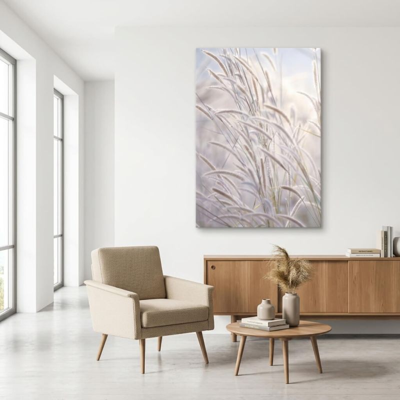 Tableau photographique de graminées beige et bleu dragée, accroché dans un salon clair avec un fauteuil et un mobilier en bois